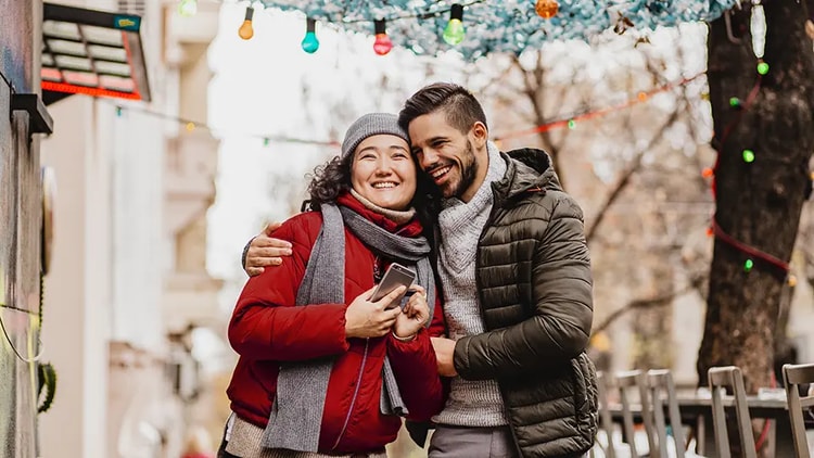 Una pareja caminando por la calle creando un envío de U-P-S en su teléfono.