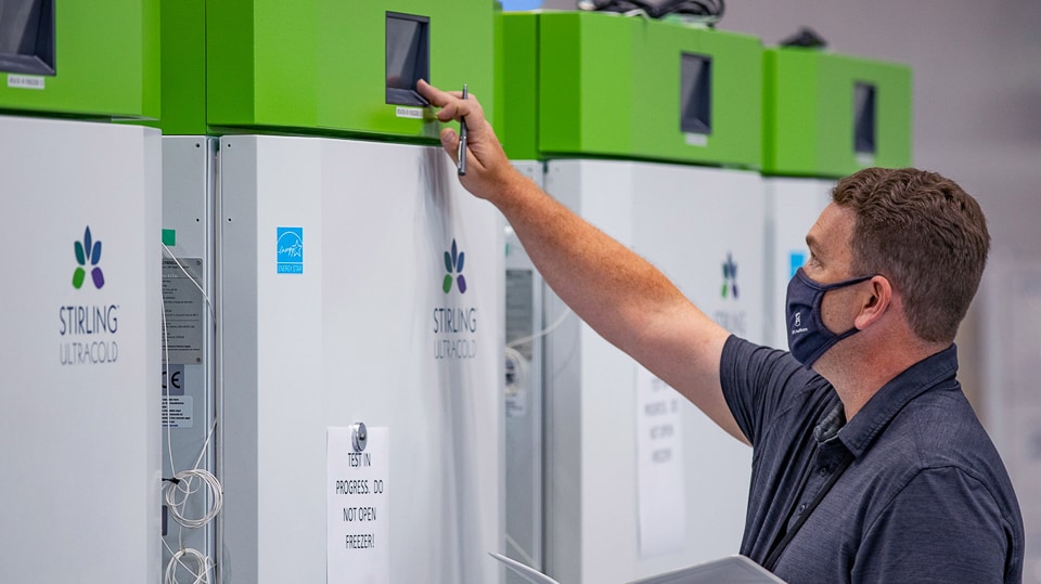 Man checking a setting on a UPS freezer storage unit.