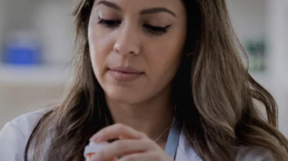 A pharmacist putting a prescription into a bag.