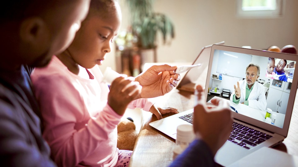 Een vader en zijn dochter voeren een telehealth-gesprek met een apotheker die uitlegt hoe hij zijn nieuwe recepten moet gebruiken.