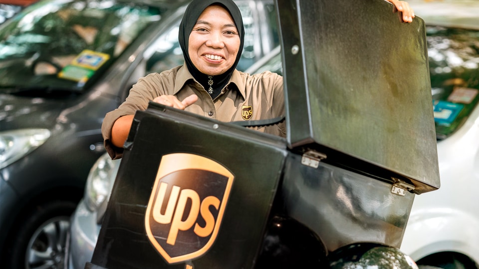 A UPS team member on a motorcycle delivers a refrigerated box of critical healthcare supplies.