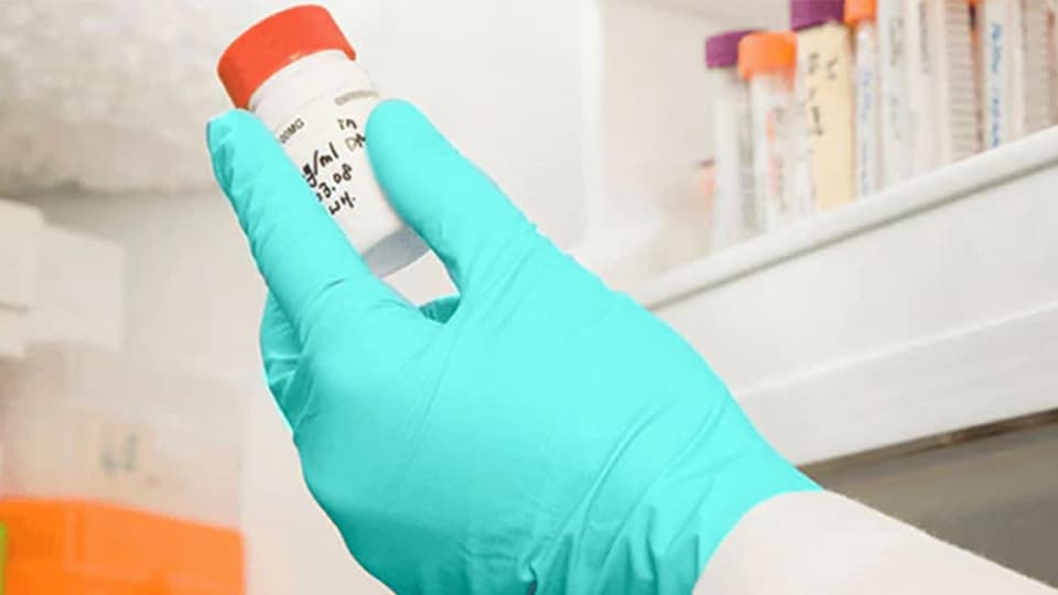 A researcher takes a lab sample out of freezer