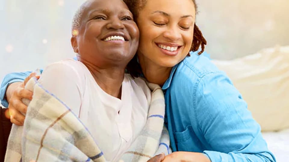 A woman hugs her mother in their home.