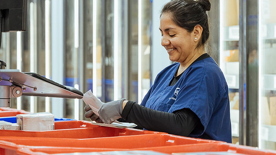 A woman in a UPS Healthcare uniform sorting orders.