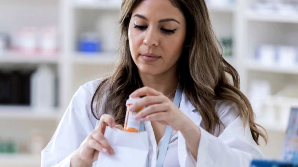 A pharmacist placing a prescription in a bag for a customer