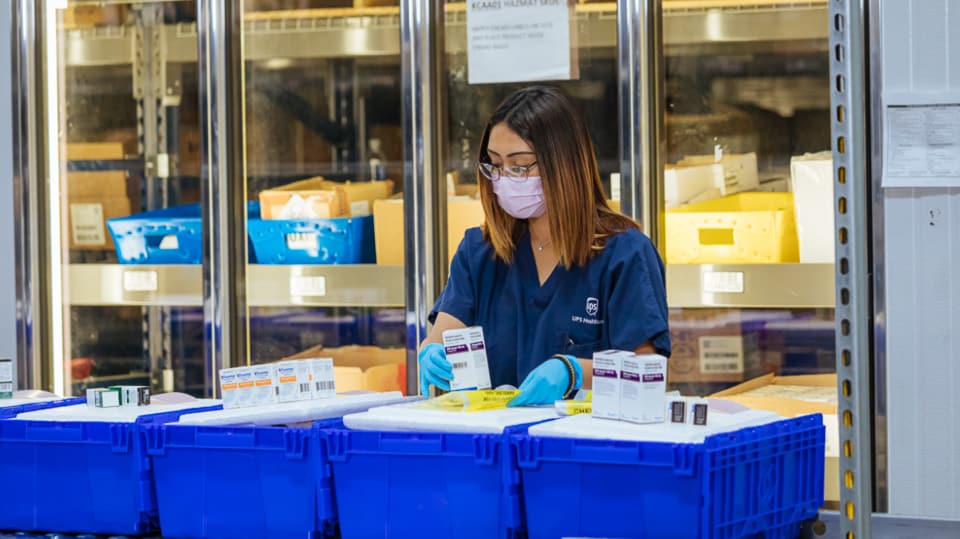 A woman places pharmaceuticals into cold chain packaging.