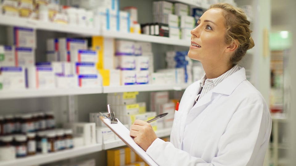 A pharmacist checking her inventory of pharmaceutical medicines