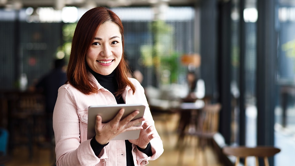 Woman smiling while holding a tablet