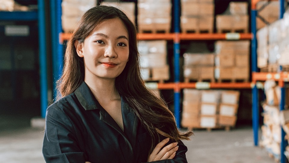 Logistics manager standing in warehouse with arms crossed