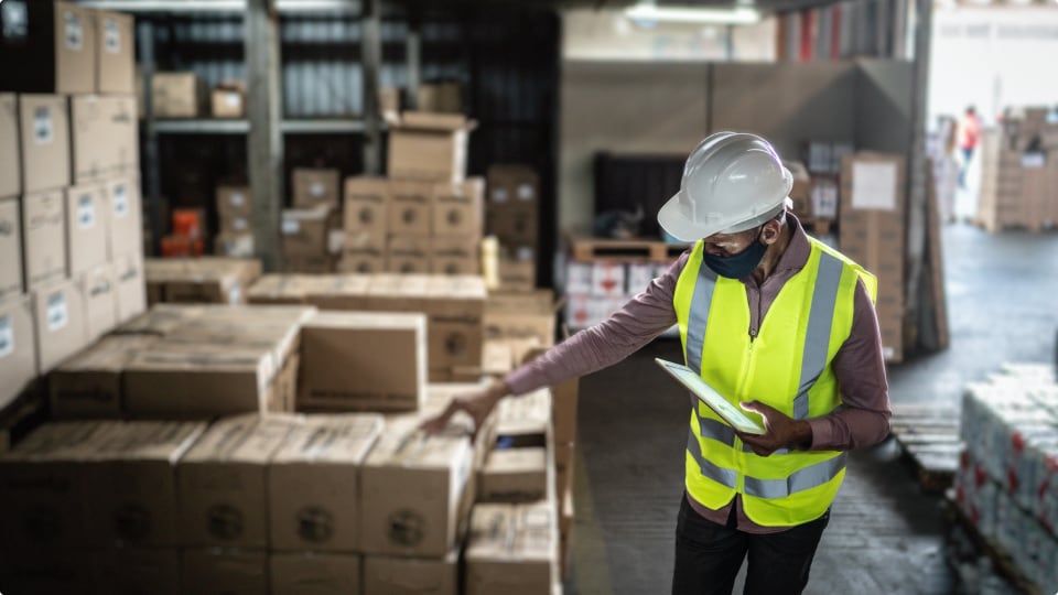 gerente de almacén sosteniendo un portapapeles con trabajadores de fondo