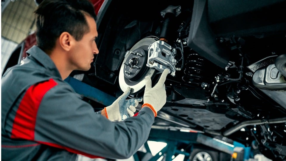 Mecánico trabajando en un automóvil levantado en un taller de reparación de automóviles