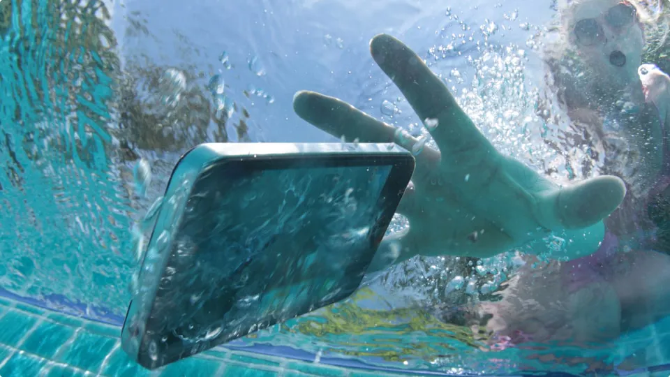 Una mujer deja caer su smartphone en la piscina