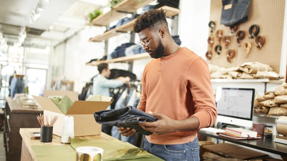 propietario de tienda de marca de jeans contemporáneos empacando pedido para recolección