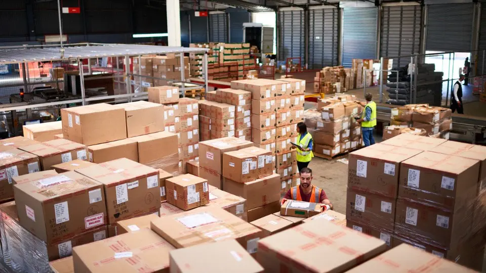 Foto de personas trabajando en un gran depósito lleno de cajas