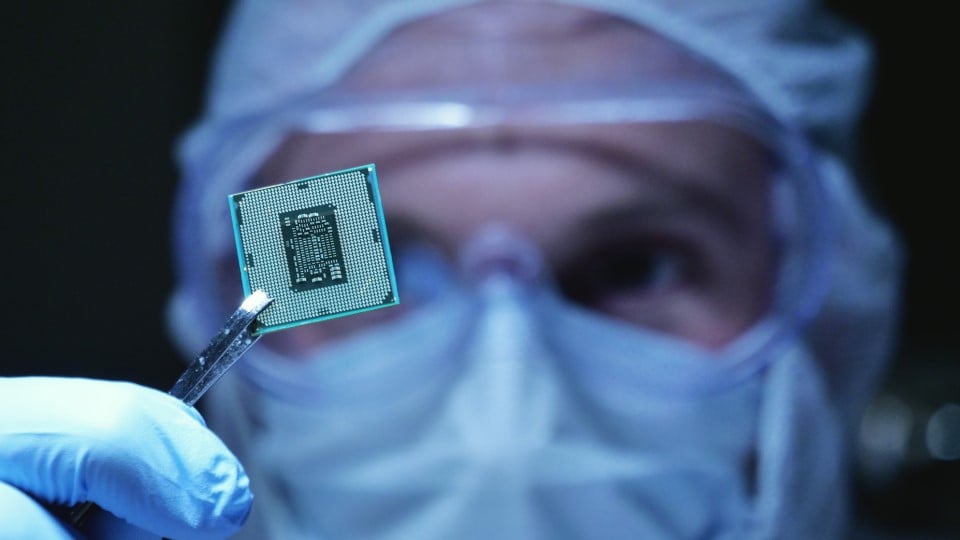 ingeniero de fabricación sosteniendo un microchip en un entorno estéril