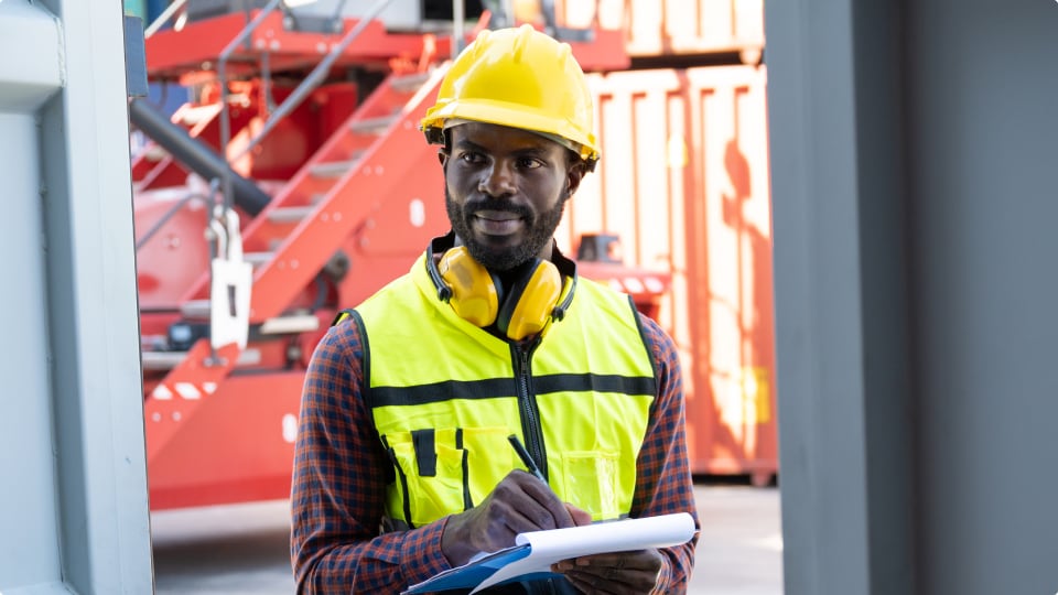 Foreman uses clipboard to takes notes on the blue shipping container