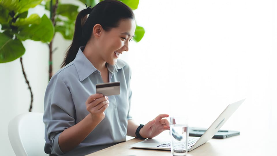 woman in front of computer with credit card