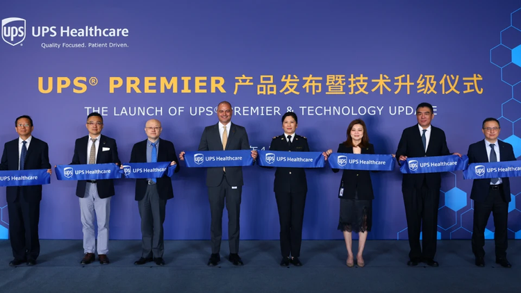 a group of people holding banners celebrating the expansion of UPS Premier