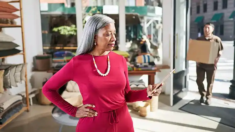 Femme âgée vêtue d’une robe rouge regardant un iPad