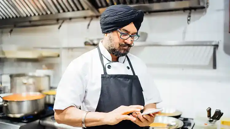 Cuisinier dans la cuisine regardant son téléphone