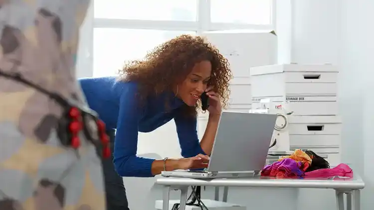 Femme parlant au téléphone et regardant un ordinateur portable