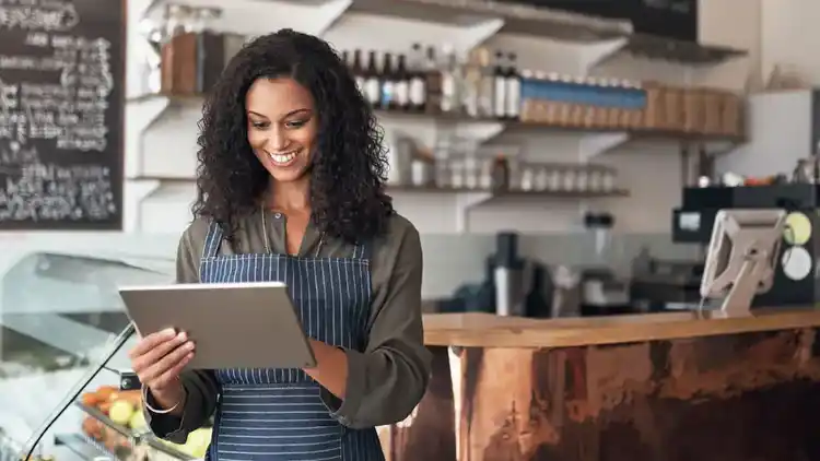 Lachende vrouw aan het werk in restaurant, op tablet.