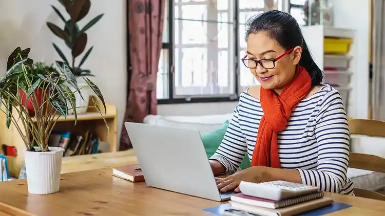 Person looking at their laptop to ship packages.