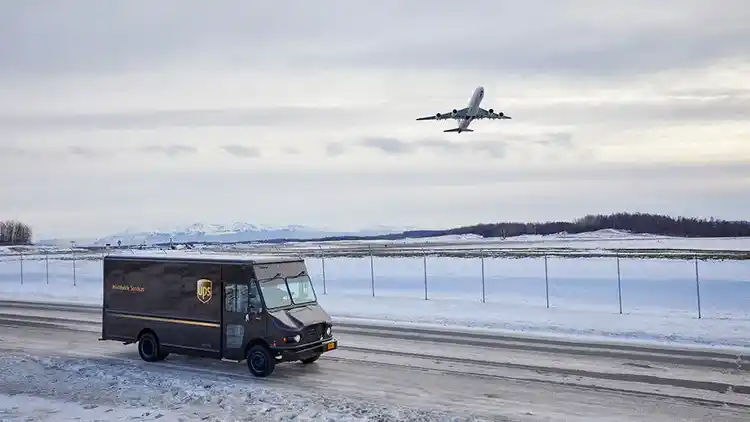 A UPS truck driving in snow as an aeroplane takes off