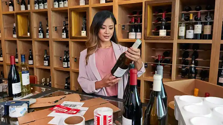 Femme regardant une bouteille de vin dans un établissement de vente au détail