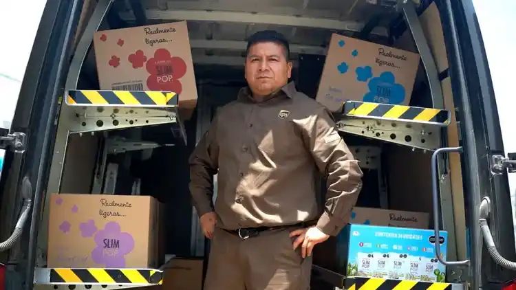 Un conductor de UPS de pie en la parte de atrás de su furgoneta.