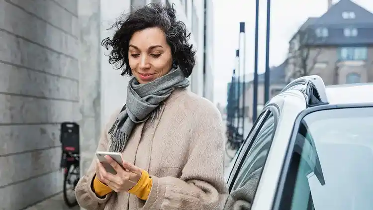 Žena na ulici se dívá na telefon