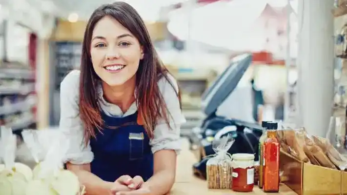 A young woman happily greeting customers in a grocery store