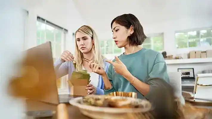 Two young women discussing business prospects while eating food