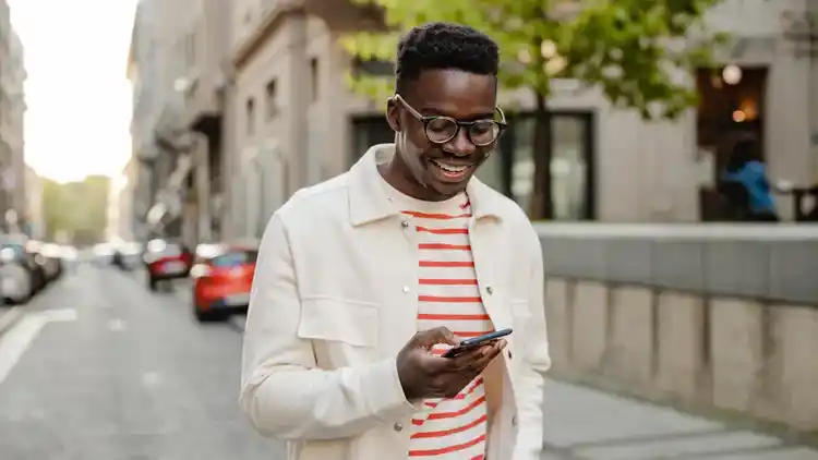 Person outside using their mobile phone to sign into UPS.com in order to hold a delivery.