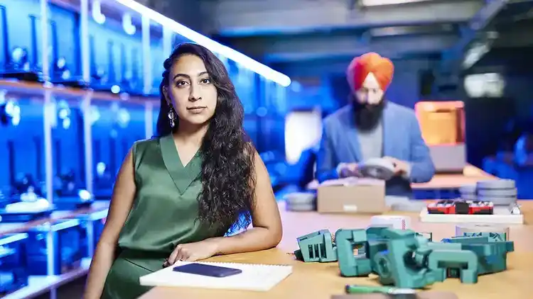 Woman stands next to table.