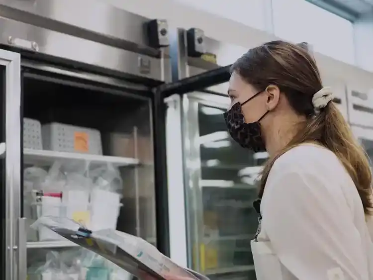 A woman holding a clipboard observing medications