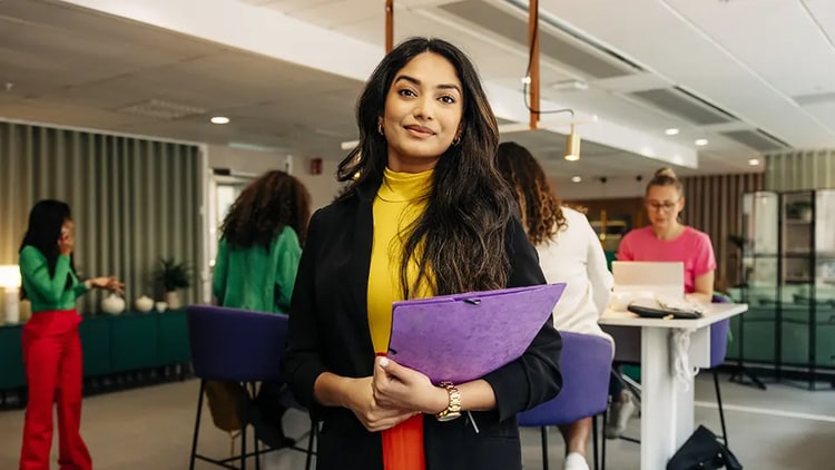 Woman in an office holding a purple folder