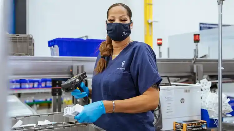 UPS Healthcare worker loading pharmaceutical products into a crate