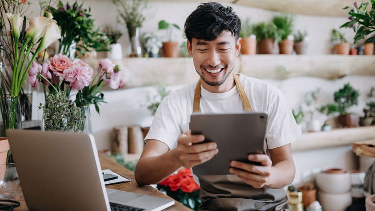 A flower shop business owner looking at their tablet.