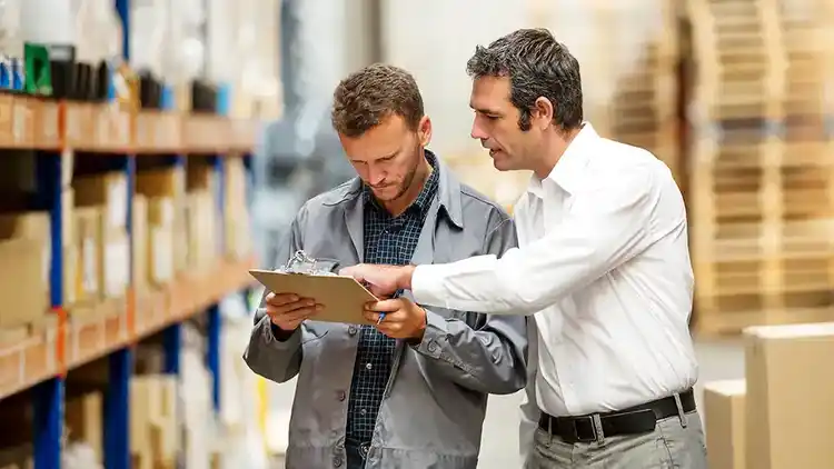 Two men look at a clipboard in a warehouse