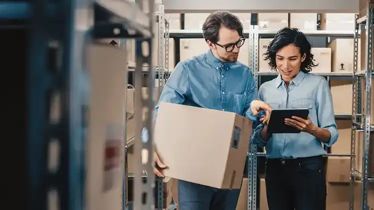 Two people holding a tablet and a box