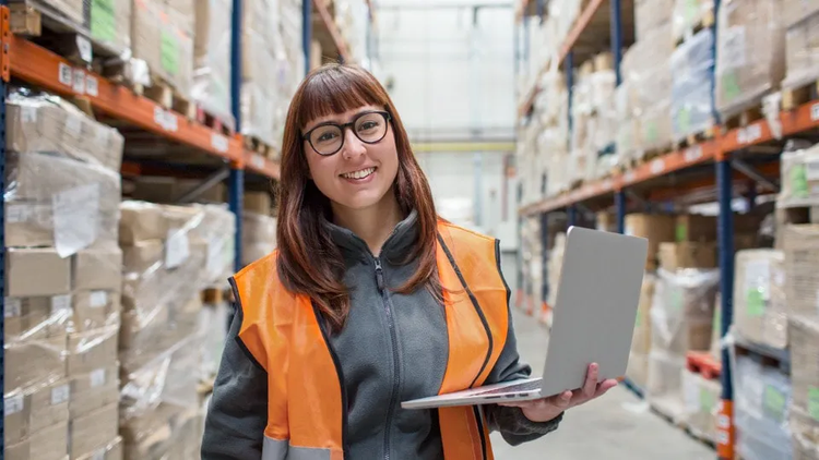 woman in a warehouse holding a laptop